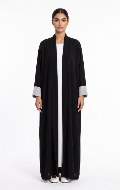 Full-length front view of a classic black open-front abaya with patterned contrast cuffs
