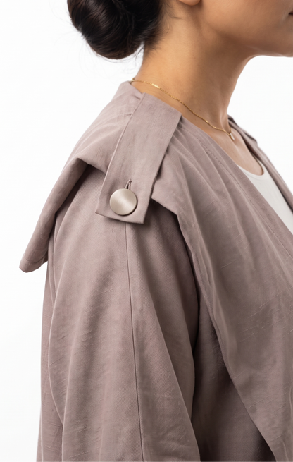 Close-up of shoulder tab with matte accent button and wide cascading collar on taupe linen abaya